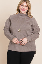 Plus size woman in cozy taupe turtleneck sweater with ribbed details, styled with black pants and gold necklace