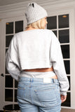 Plus size woman in gray cropped sweatshirt, beanie, and light wash jeans, back view