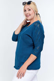 Plus size woman in blue knit top with lace sleeves and white pants