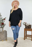 Plus size woman in black knit top, ripped jeans, and hat, styled for casual wear