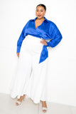 Plus size woman in blue satin blouse and white wide-leg pants, stylish outfit for confident look