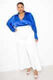 Plus size woman in blue satin blouse and white wide-leg pants, stylish and confident outfit