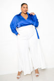 Plus size woman in blue satin blouse and white wide-leg pants, stylish and confident outfit