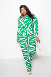 Plus size woman in green and white zebra print jumpsuit with white heels and handbag