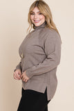 Plus size woman in cozy taupe turtleneck sweater with side slits, styled with black pants and gold necklace